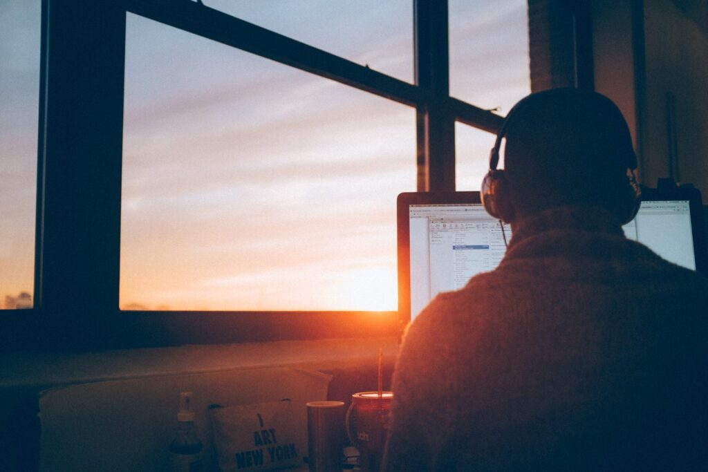 man photographed from behind, sitting in front of a computer screen in sunset ads interactive ad monetization platform