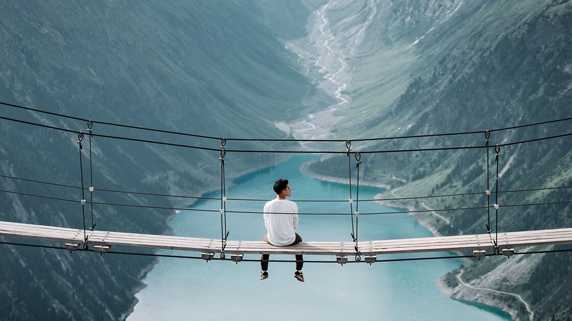 man sitting on bridge near mountains ads interactive ad monetization platform