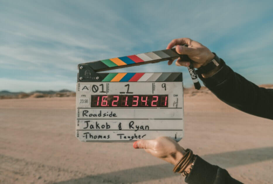 a person holding a clapper in the middle of a desert for video shooting ads interactive ad monetization platform